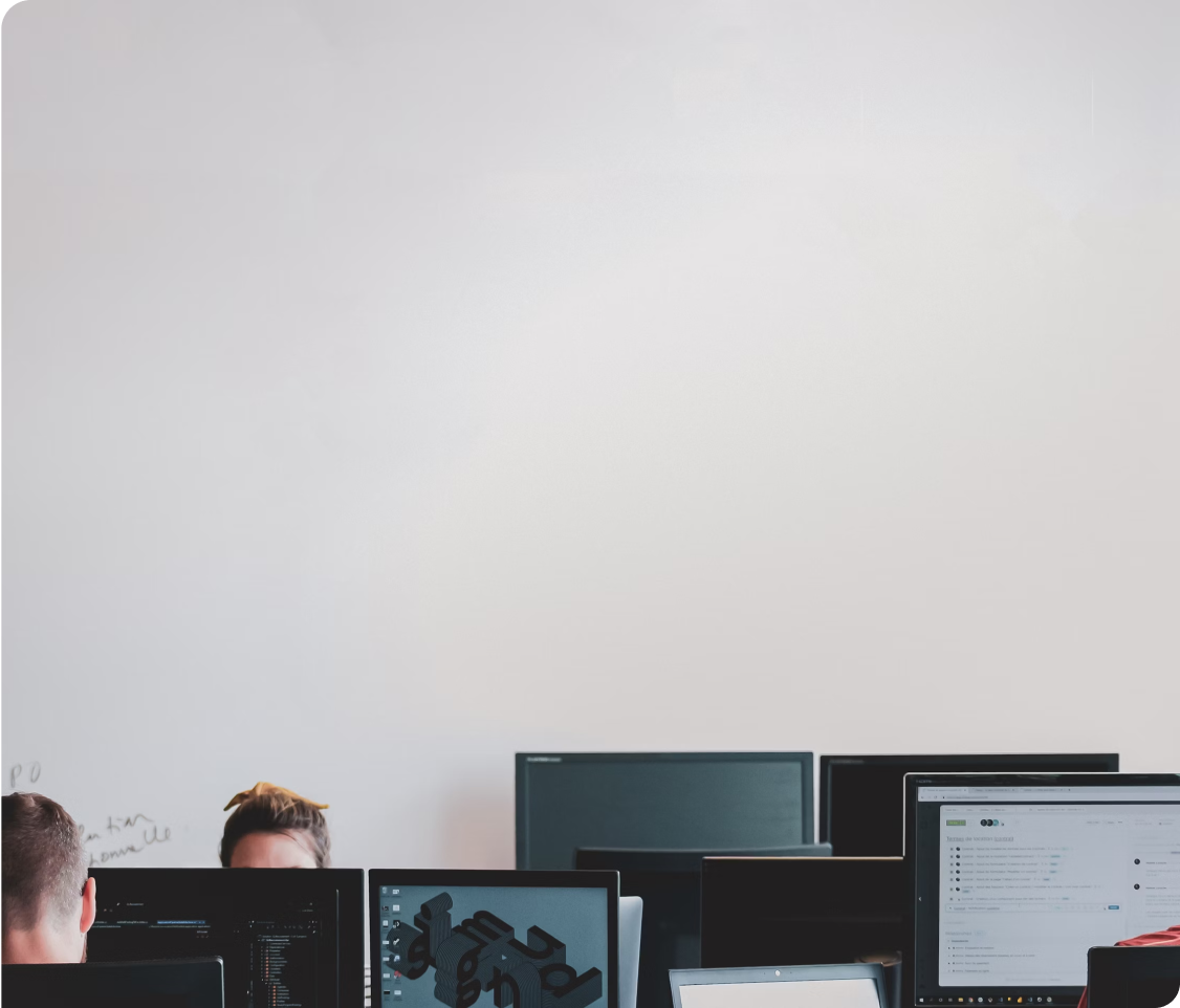 People working in front of computer monitors in an office setting.