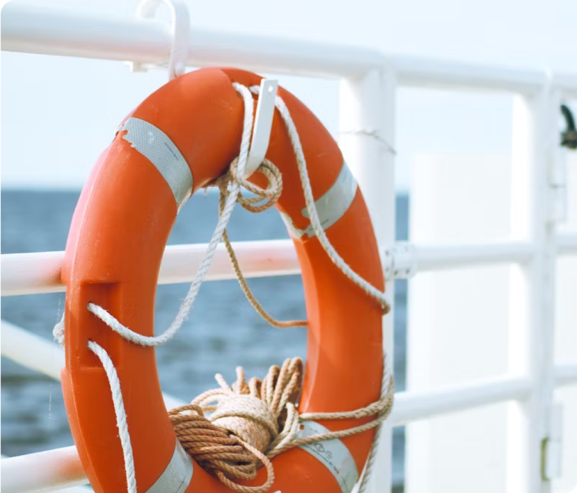 Orange lifesaver ring attached to a railing by the sea.